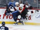 Dylan Samberg (54) des Jets de Winnipeg et Mark Kastelic (12) des Sénateurs d'Ottawa entrent en collision lors de la première période du match préparatoire de la LNH à Winnipeg jeudi, 