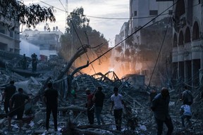 Des gens marchent au sommet des décombres d’une tour détruite lors d’une frappe aérienne israélienne dans la ville de Gaza, le 7 octobre 2023.
