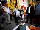 Des gens effacent une pancarte représentant le Premier ministre indien Narendra Modi lors d'un rassemblement sikh devant le consulat indien à Toronto pour sensibiliser l'opinion à l'implication présumée du gouvernement indien dans le meurtre du séparatiste sikh Hardeep Singh Nijjar en Colombie-Britannique le 25 septembre 2023.