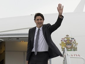 Justin Trudeau salue alors qu'il monte à bord d'un avion du gouvernement
