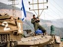 Un soldat de l’armée israélienne tient des obus au sommet de la tourelle d’un char de combat Merkava alors qu’une colonne de chars est rassemblée mercredi dans le nord d’Israël, près de la frontière avec le Liban.