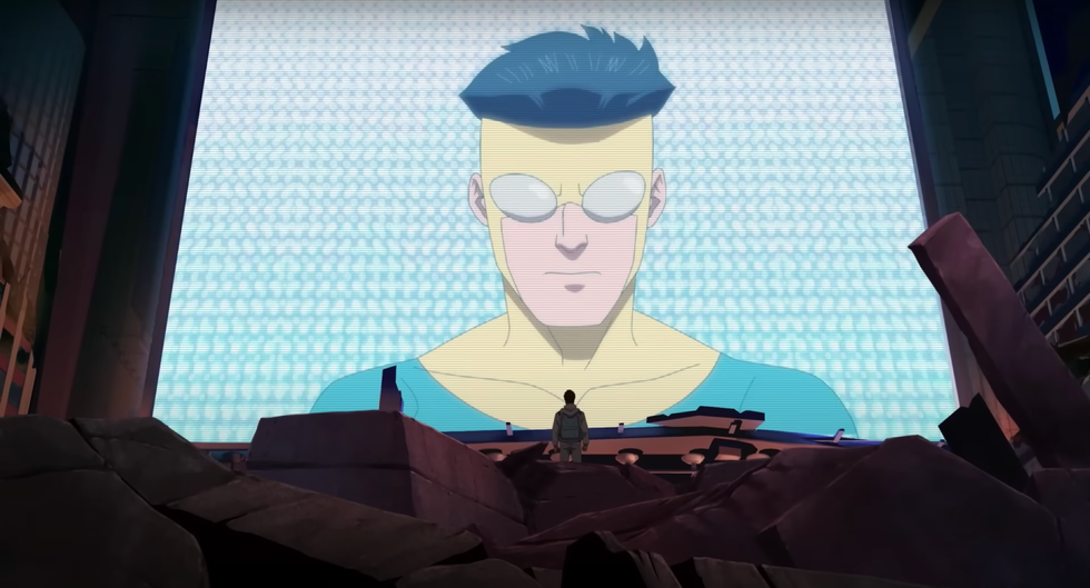 une image fixe du personnage animé Mark, un jeune homme aux cheveux noirs portant un costume de super-héros jaune et bleu et des lunettes grises, sur grand écran devant une autre personne, de la saison 2 de la série télévisée invincible
