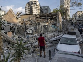 Des Israéliens inspectent les décombres d’un bâtiment un jour après qu’il a été touché par une roquette tirée depuis la bande de Gaza, à Tel Aviv, Israël, le dimanche 8 octobre 2023.