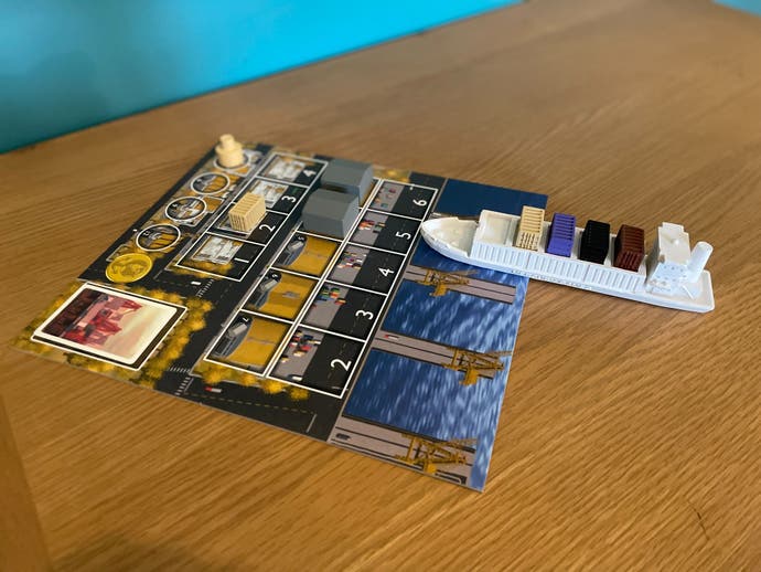Un plateau du jeu de société Container (Jumbo Edition), sur une table et avec une miniature de porte-conteneurs garée dessus.