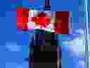Un drapeau du Canada est photographié avec la Tour de la Paix sur la Colline du Parlement à Ottawa, le lundi 12 avril 2021.