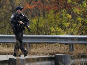 Un policier marche le long d'une route rurale lors d'une chasse à l'homme pour le suspect des fusillades de masse de mercredi, le jeudi 26 octobre 2023, à Lisbonne, dans le Maine.  La fusillade a eu lieu dans un restaurant et un bowling à proximité de Lewiston, dans le Maine.