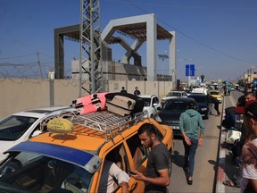 Des Palestiniens munis de passeports étrangers arrivent à la porte de Rafah dans l'espoir de passer en Égypte alors que les attaques israéliennes sur la bande de Gaza se poursuivent, le 14 octobre 2023.
