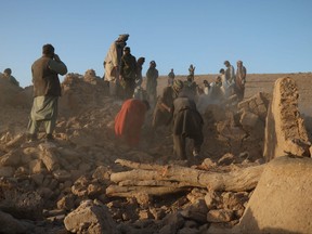 Des habitants afghans débarrassent les débris d'une maison endommagée après le tremblement de terre dans le village de Sarbuland, district de Zendeh Jan, province d'Herat, le 7 octobre 2023.