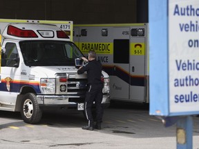 Un ambulancier paramédical travaille sur un ordinateur portable sur le capot de son ambulance, à l'extérieur du service des urgences du campus civique de l'Hôpital d'Ottawa, à Ottawa, le lundi 16 mai 2022.