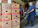   Des travailleurs chargent des appartements remplis de nourriture provenant de dons et d'épiceries dans l'entrepôt de la Banque alimentaire d'Ottawa, près du boulevard Saint-Laurent.