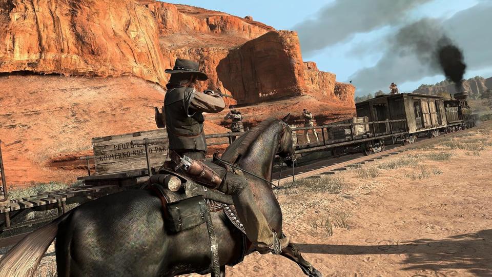 Capture d'écran du gameplay de Red Dead Redemption porté sur PS4.  John Marston (le protagoniste) monte à cheval et pointe un fusil sur un train en marche tandis que des hors-la-loi lui ripostent.  Une fumée sombre s'échappe du moteur du train et un terrain rocheux du sud-ouest est visible derrière.
