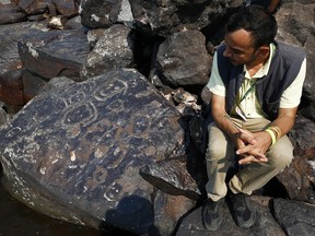L'archéologue Jaime Oliveira est assis à côté de peintures rupestres sur le site archéologique de Ponta das Lajes, dans la zone rurale de Manaus, au Brésil, le samedi 28 octobre 2023.