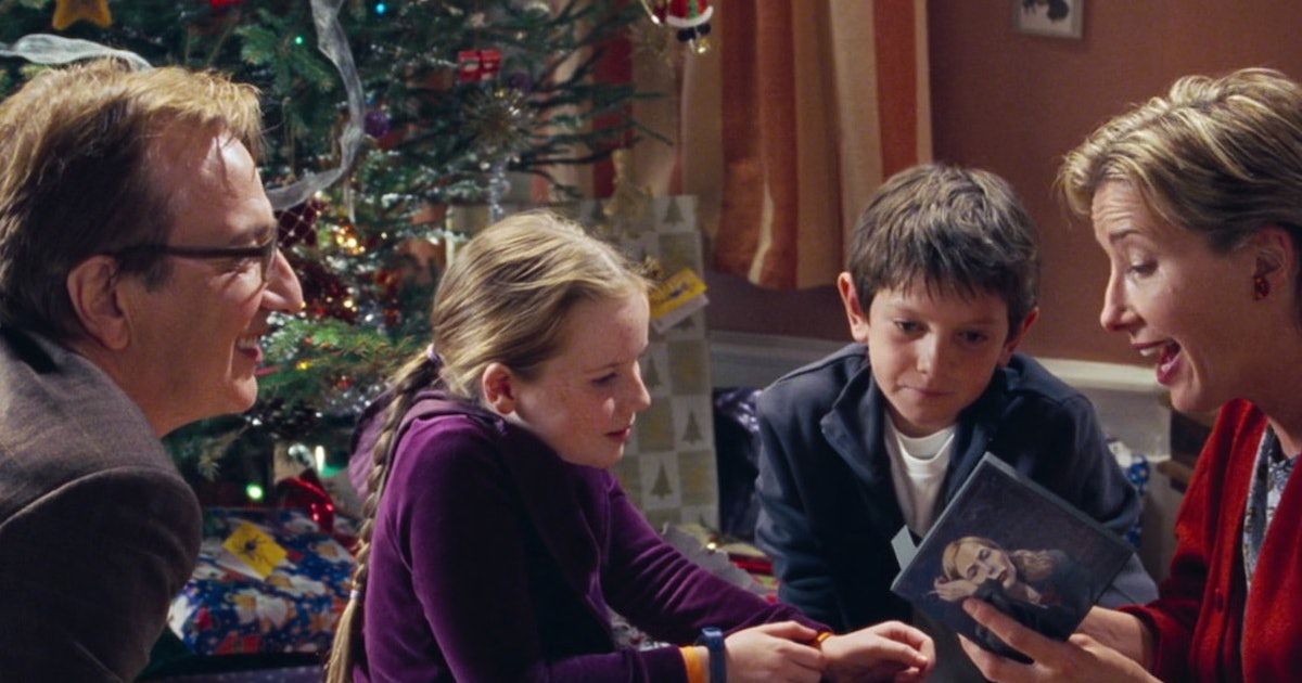 Alan Rickman regarde Emma Thompson ouvrir un CD, sous les yeux de leurs enfants.  il y a un sapin de Noël en arrière-plan