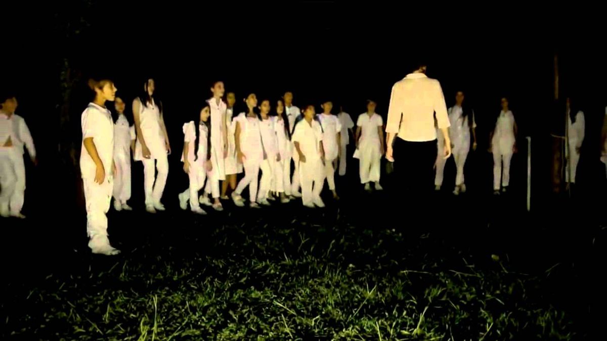 Un groupe d'enfants en tenue blanche exécutent un rituel étrange la nuit dans l'herbe dans Limbo (2014)