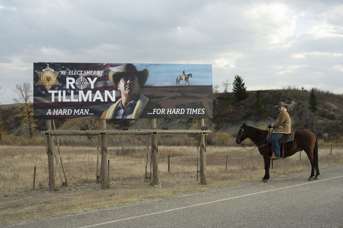 Jon Hamm dans le rôle du shérif Roy Tillman est assis sur un cheval au bord de la route avec son propre panneau d'affichage de campagne à côté de lui dans la série FX Fargo saison 5. 