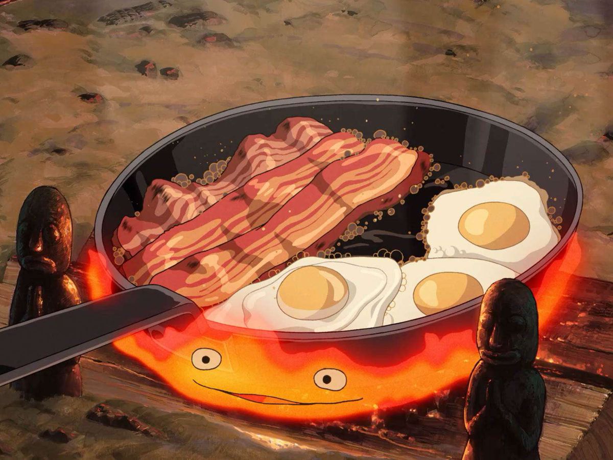 Une poêle animée d'œufs et de bacon épais mijotant sur un feu avec une bouche et deux yeux dans Howl's Moving Castle.