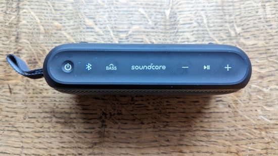 Test Anker Soundcore Motion 300 : un haut-parleur noir avec grille argentée apparaît sur une surface en bois.