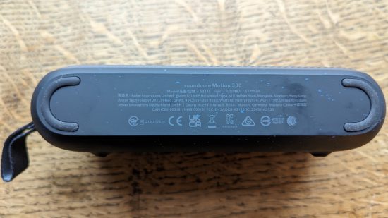 Test Anker Soundcore Motion 300 : un haut-parleur noir avec grille argentée apparaît sur une surface en bois.