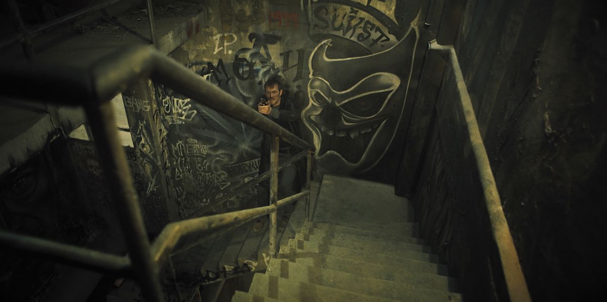Joel Kinnaman monte un escalier avec une arme à feu dans Silent Night.  L'image vient de la butée de l'escalier, avec Kinnaman vers le bas.