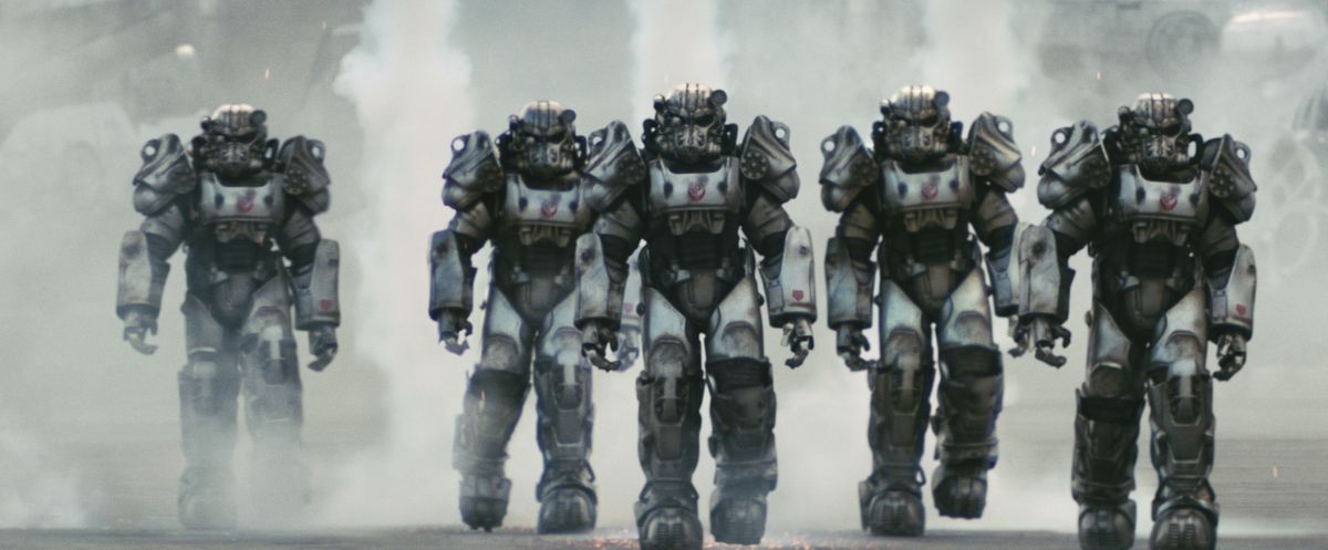 Une ligne de soldats de la Confrérie de l'Acier en armure assistée avançant dans la série télévisée Fallout