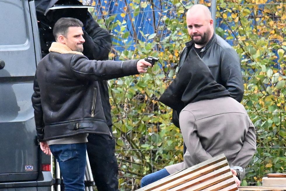 Ciaran Griffiths dans le rôle de Damon Hay pointe une arme sur Sam Robertson dans le rôle d'Adam Barlow, filmant des scènes de rue du couronnement