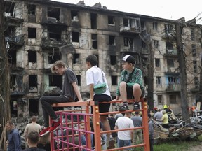 Des enfants ukrainiens enlevés par la Russie lors de l'assaut contre leur pays partagent l'histoire de leur captivité avec des parlementaires canadiens, dans l'espoir qu'ils aideront à en sauver d'autres.  Des enfants regardent la scène de la dernière attaque à la roquette russe qui a endommagé un immeuble à plusieurs étages à Kryvyi Rih, en Ukraine, le mardi 13 juin 2023.