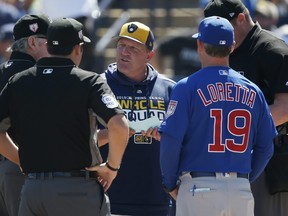 L'entraîneur de banc des Milwaukee Brewers, Pat Murphy, s'entretient avec l'entraîneur de banc des Cubs de Chicago, Mark Loretta, et les arbitres avant un match d'entraînement de printemps.
