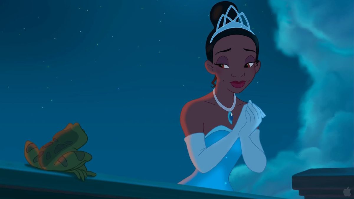 Tiana, une femme noire portant un diadème, une robe argentée et des gants d'opéra blancs, joint ses mains et sourit à une grenouille à côté d'elle dans La Princesse et la grenouille de Disney