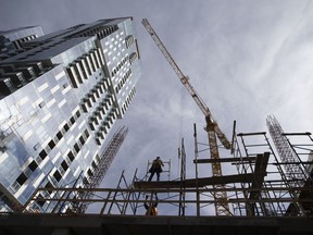 Un ouvrier du bâtiment érige un échafaudage sur un immeuble de copropriétés en construction au centre-ville de Montréal.