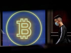 Un banlieusard passe devant un affichage numérique de crypto-monnaie Bitcoin dans le quartier central de Hong Kong, en Chine.