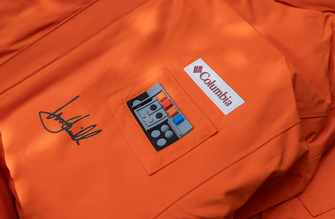 Un gros plan de l'autographe de Mark Hammill sur une veste orange Columbia