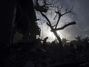 Des Palestiniens inspectent les dégâts d'une maison détruite suite aux frappes aériennes israéliennes dans la ville de Khan Younis, dans le sud de la bande de Gaza, le mercredi 22 novembre 2023.