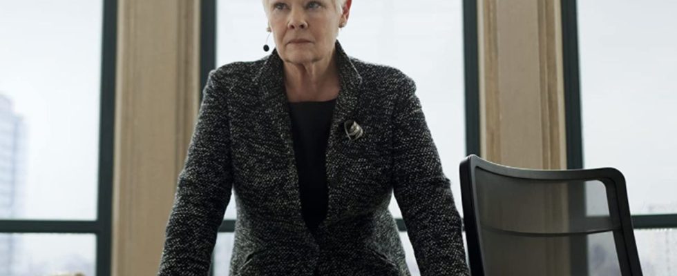 Dame Judi Dench standing at her desk, with Jack the Bulldog in Skyfall.
