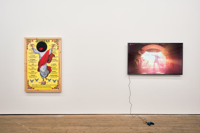 Art de Larry Achiampong montrant un Jésus blanc, mais avec son visage couvert d'un cerne noir avec des lèvres rouge vif.  À côté, sur le mur d'une galerie, se trouve un écran de télévision exécutant le jeu BioShock Infinite.