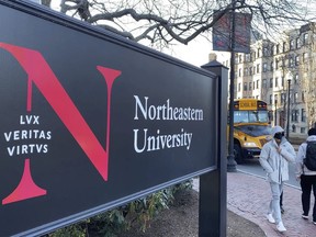 les piétons marchent près d’un panneau de l’Université Northeastern
