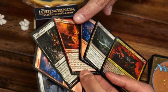 A hand points to Magic: The Gathering cards someone is holding