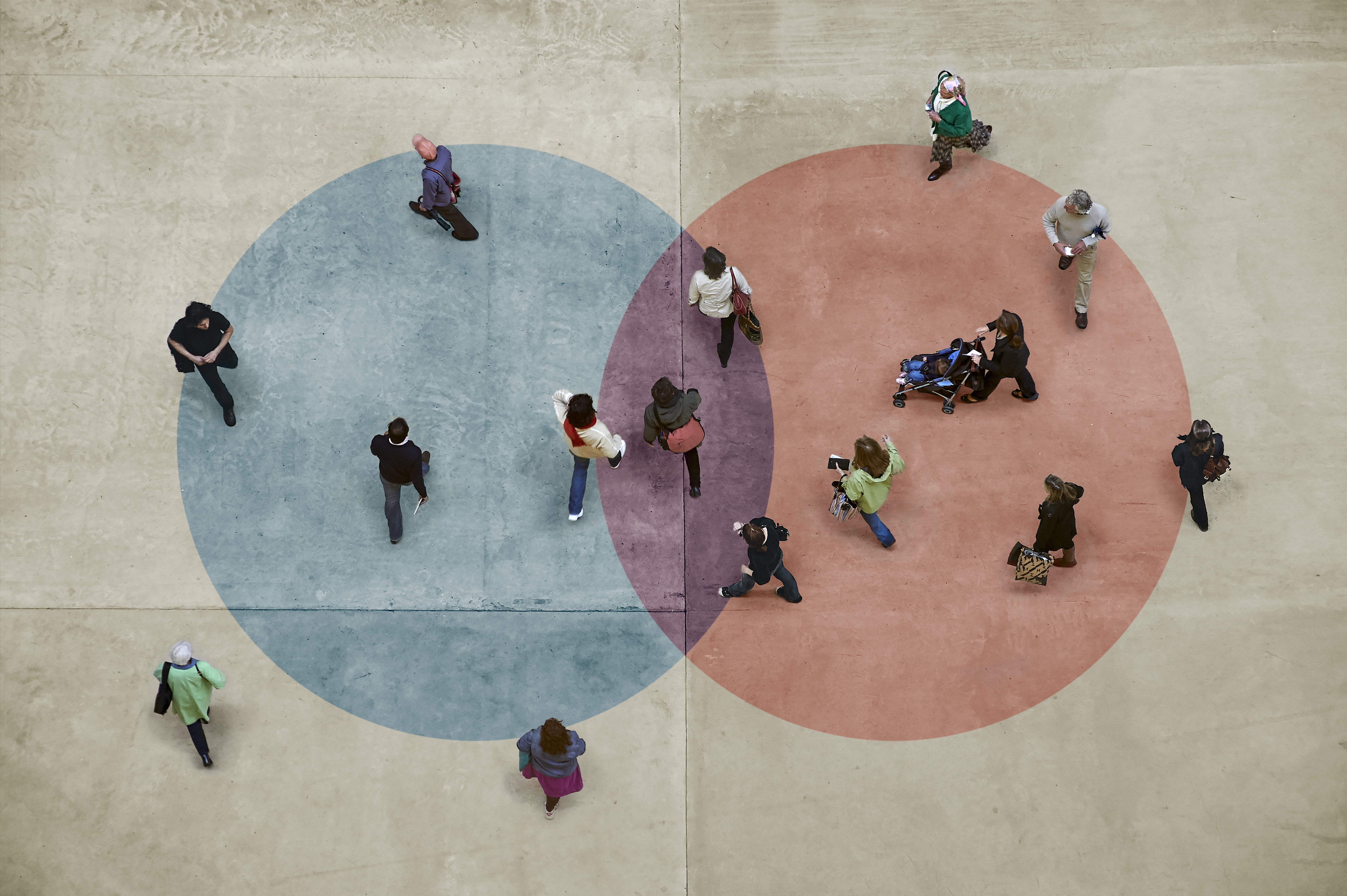 Image de cercles bleus et rouges superposés avec des personnes debout dans et autour des deux.