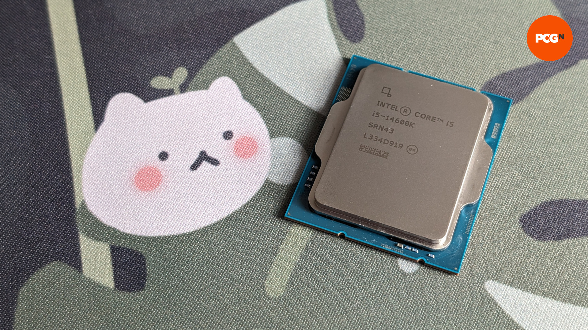 L'Intel Core i5 14600K (à droite) sur un fond feuillu avec un personnage ressemblant à un chat blanc (à gauche)