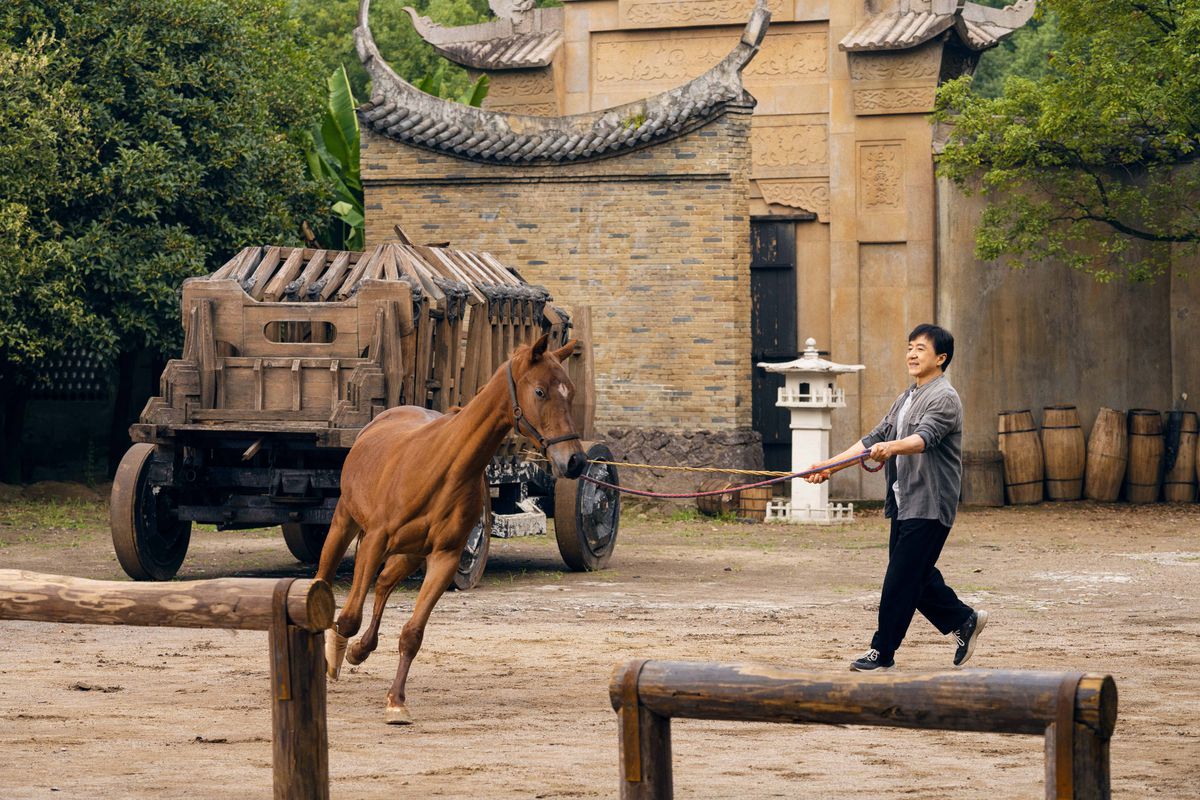 Un cheval galope dans une zone dégagée pendant que Jackie Chan donne des instructions dans Ride On.