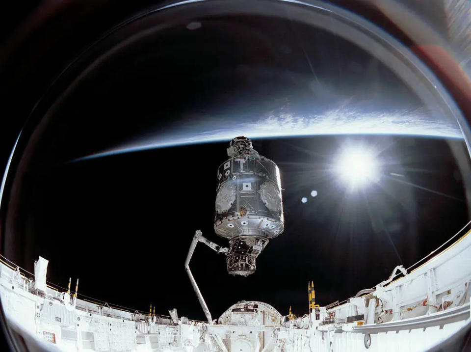Photo prise à bord de l'ISS lors de son assemblage initial.  Un module est placé verticalement au centre avec la Terre derrière lui.