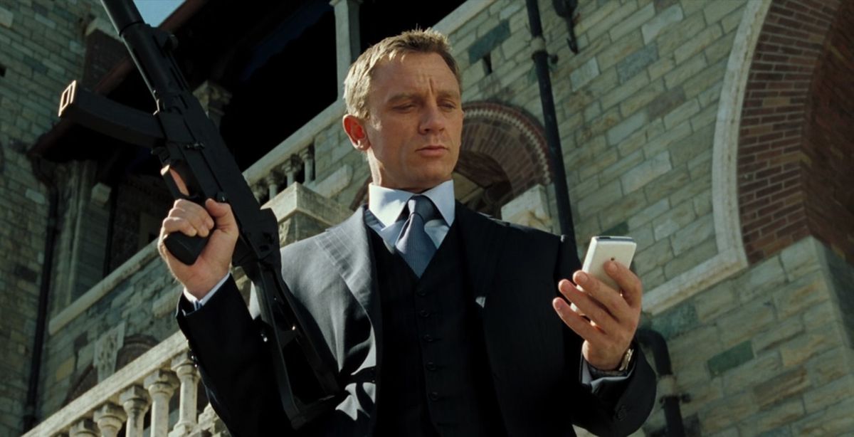 Daniel Craig dans le rôle de James Bond dans Casino Royale, vêtu d'un costume et vérifiant son téléphone tout en tenant une arme à feu