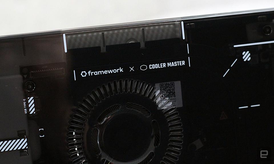 Gros plan du logo Framework x Cooler Master sur le devant du boîtier devant un mur peint en gris.