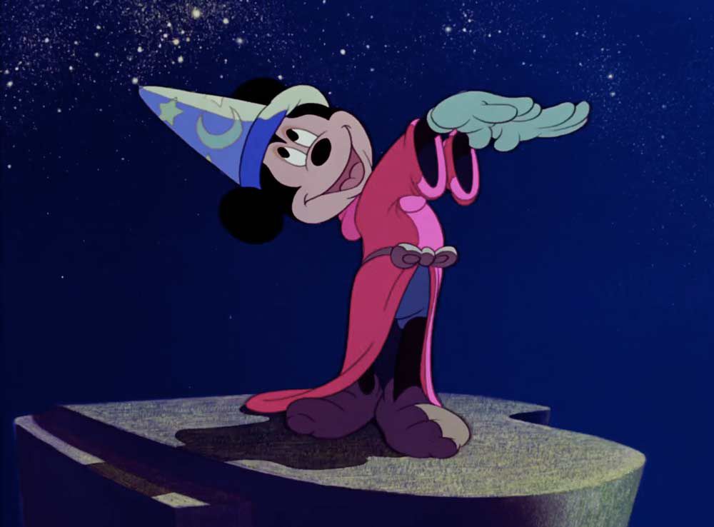 Mickey Mouse coiffé d'un chapeau de sorcier agitant ses bras comme un chef d'orchestre dans Fantasia.