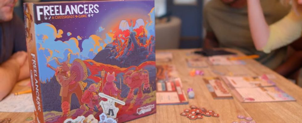 The Freelancers box on a wooden table beside the game board, tokens, and more as people play
