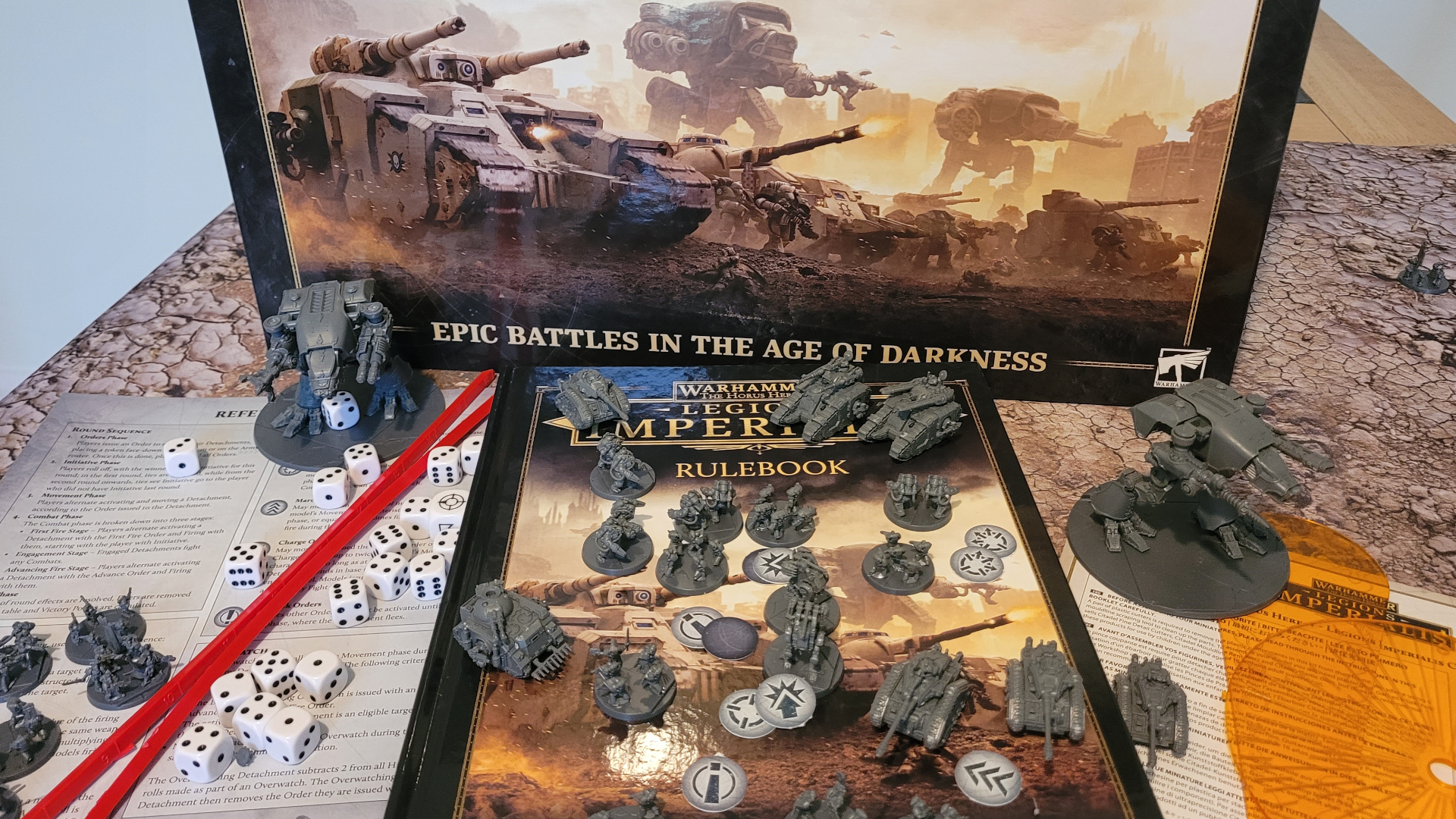 La boîte Legions Imperialis, le livret de règles, les miniatures, les jetons et les outils sur une table