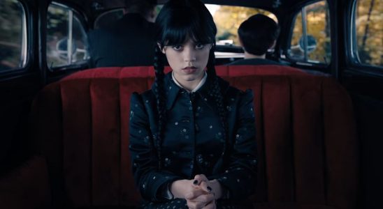Jenna Ortega as Wednesday sitting in a car doing her signature stare.