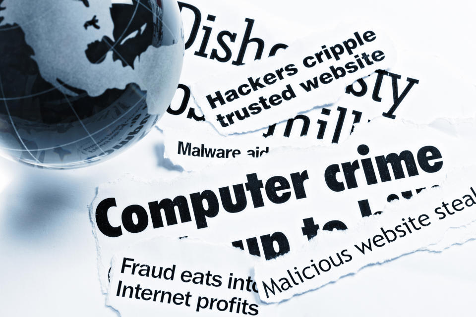Un presse-papier en forme de globe en verre bleu repose sur des titres imprimés couvrant des aspects de la criminalité sur Internet et liée à l'informatique.