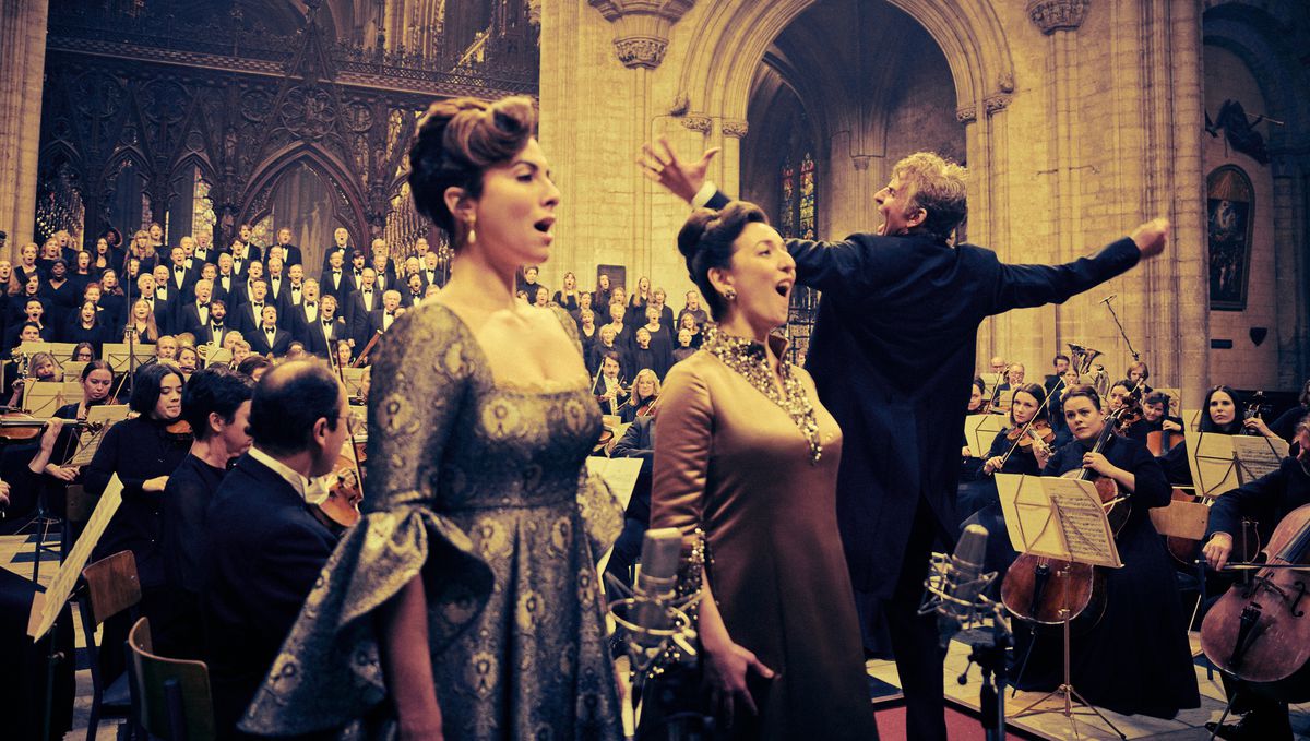 Bradley Cooper dans le rôle de Leonard Bernstein dirige de manière flamboyante dans une cathédrale alors que deux solistes habillés d'opéra (Isabel Leonard et Rosa Feola) chantent devant lui, un orchestre l'entoure et un chœur d'hommes en smoking chante en arrière-plan dans Maestro de Netflix.