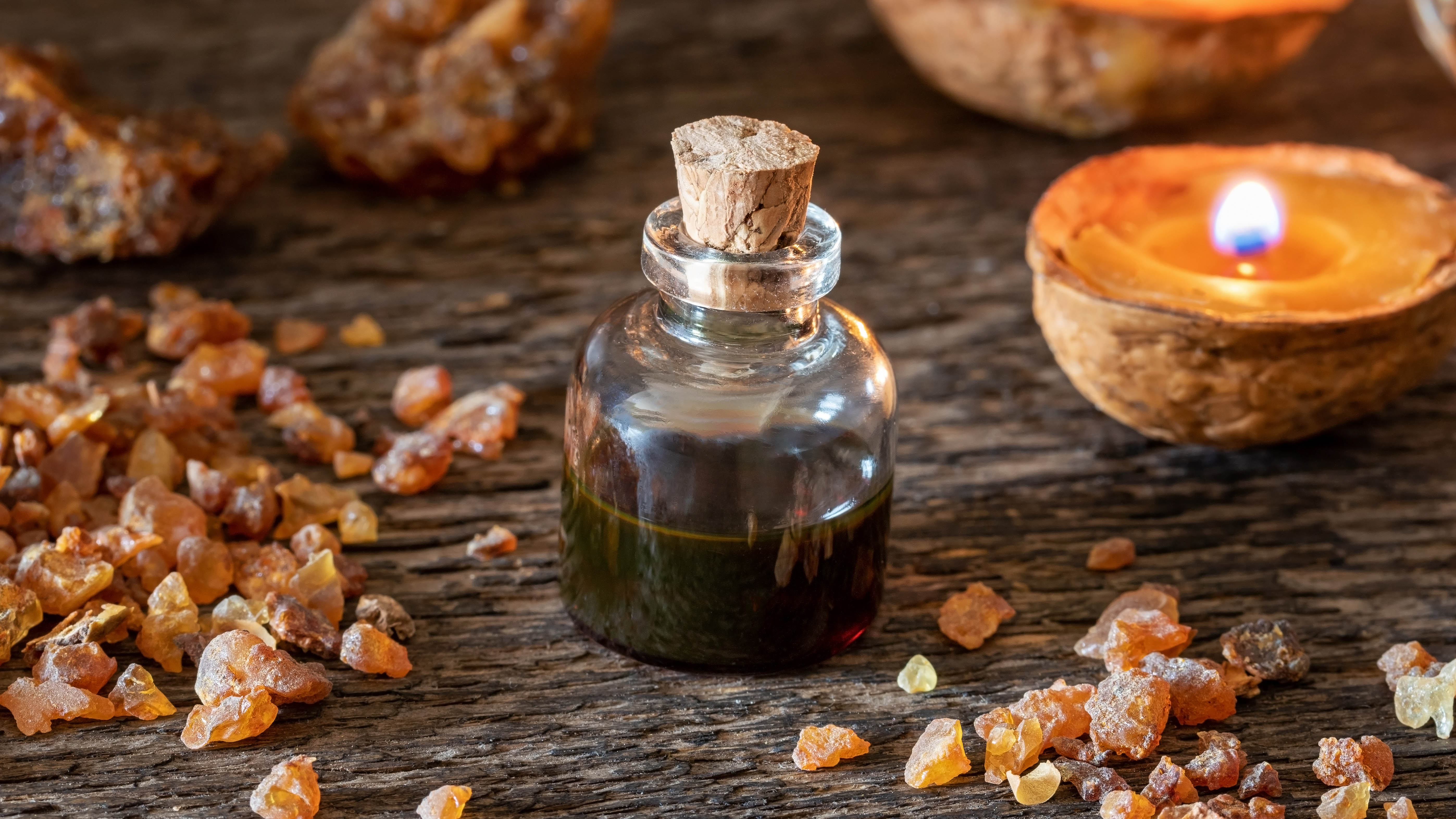 Une bouteille d'huile essentielle de myrrhe à côté d'une bougie