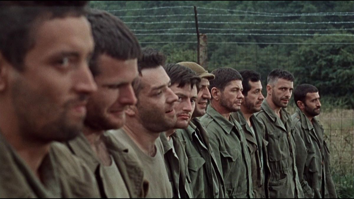 Un gros plan de plusieurs soldats faisant la queue à côté d’une clôture de barbelés dans The Dirty Dozen.